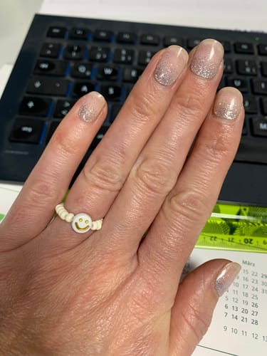 Kundin zeigt ihre Hand mit den „Magical Dusting“ UV-Gelfolien, die einen hübschen silbernen Glitzerverlauf haben.