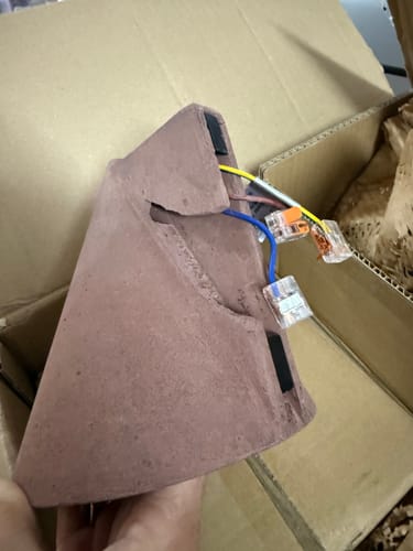 Recensent houdt de rode wandlamp vast en toont de kwetsbare bedrading aan de achterkant.