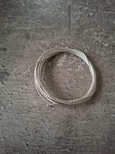 Klant toont de opgerolde Diamond Elastic Threader op een stenen ondergrond.