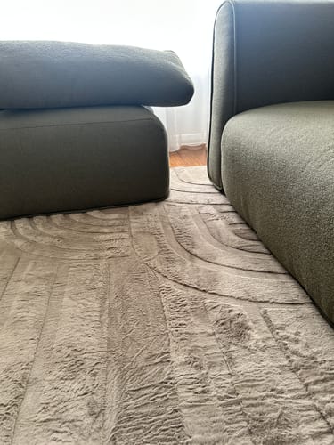 Close-up of a customer's plush Mellow Mat®, showing its carved texture next to a sofa.