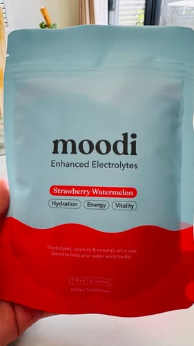 Reviewer holding the blue and red pouch of Moodi Enhanced Electrolytes in Strawberry Watermelon flavor.
