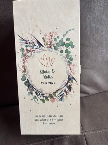 Kunde zeigt die personalisierte Holzkiste für das Leonardo Sektgläser-Set mit „Flower Wedding“ Design und bedrucktem Spruch.