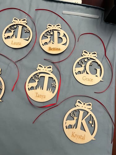 Reviewer's collection of six personalized monogram deer ornaments, each with a different name and initial engraved on them.