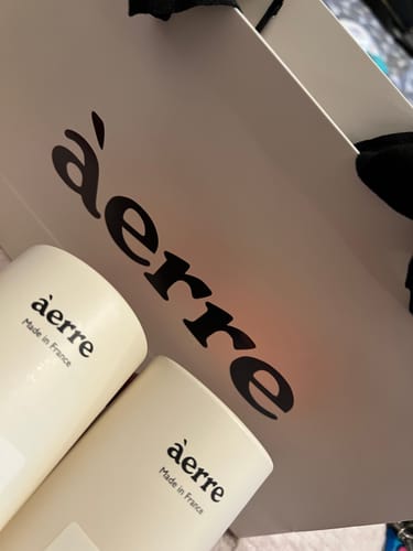Customer's close-up photo of two white Áerre perfume containers in front of the branded bag.