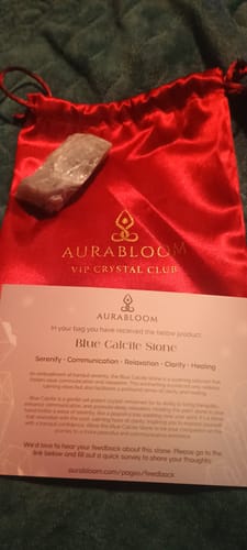 Reviewer's Blue Calcite stone from the VIP Crystal Club, displayed with a red satin bag and info card.