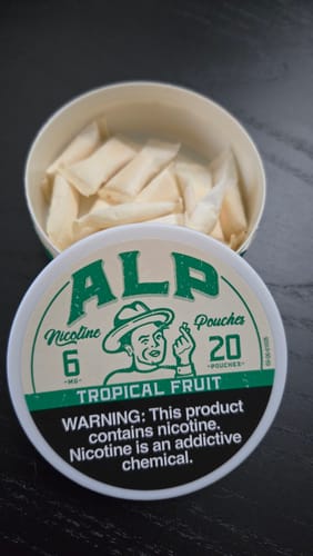 Customer's open can of ALP Tropical Fruit Nicotine Pouches, showing the individual pouches and the branded lid.