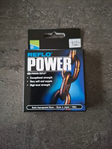 Recensent toont de verpakking van de REFLO POWER vislijn op een grijze ondergrond.