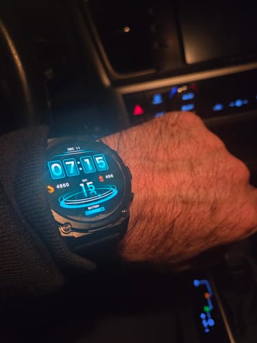 Customer's rugged Gard Pro Ultra 3 watch on their wrist, with an illuminated blue digital face inside a dark car.