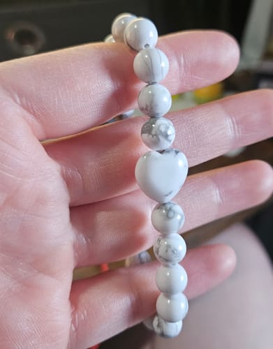 Customer holding a white marbled crystal bracelet with a central heart-shaped bead.