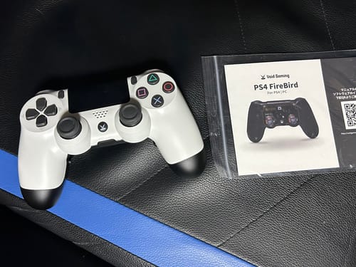 レビュー投稿者の白いPS4FireBirdコントローラー。説明書と一緒に椅子の上に置かれています。