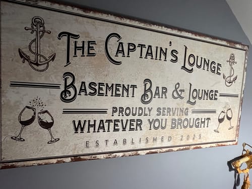 Customer's personalized, rustic Basement Bar and Lounge Sign with "The Captain's Lounge" text, hung on a wall.