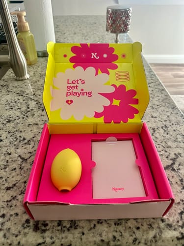Customer's Lem Clitoral Massager unboxed in its colorful packaging on a kitchen counter.