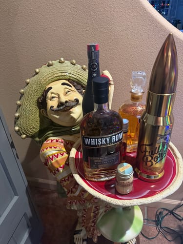 Customer's Full Bore Peanut Butter and Jalapeño Whiskey in its distinctive bullet-shaped bottle on a decorative tray.
