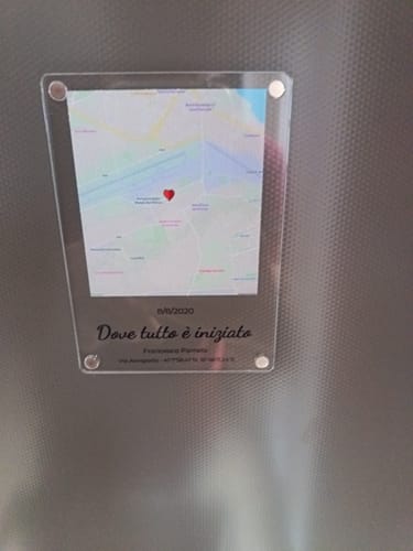 Ein Kunde zeigt seinen personalisierten Acrylmagneten „Wo alles begann“ auf einer strukturierten Metalloberfläche.