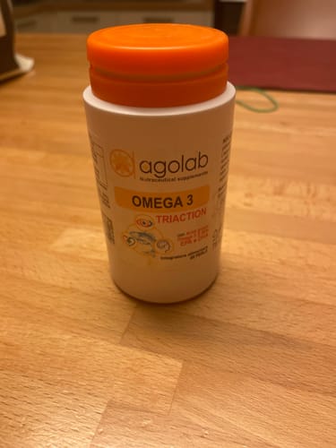 Flacone bianco di Omega 3 Tri-Action del cliente con tappo arancione, su un tavolo.