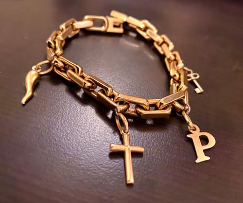 Customer's shiny Elongated Link Bracelet customized with several gold-toned charms, including a cross and the letter P.