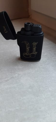 Rezensent zeigt sein schwarzes, personalisiertes Feuerzeug mit der Initiale 'U' und dem Namen 'Uwe'.