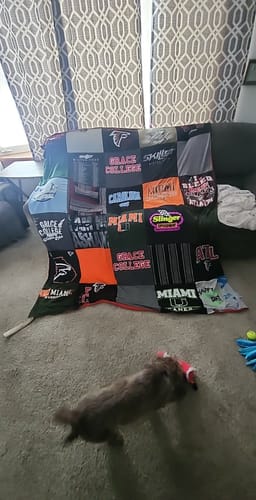Customer's colorful Premium T Shirt Quilt, made from many shirts, draped over the back of a sofa in a living room.