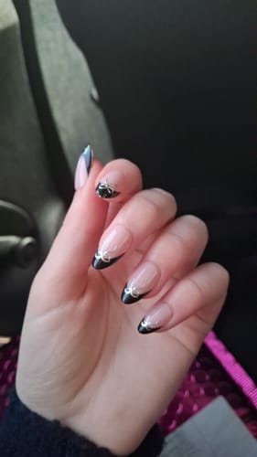 Close-up of a customer's hand wearing the Midnight Ribbon press-on nails, showing the black tips and silver ribbon design.