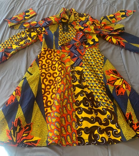 Reviewer's Gilda African Print Midi Dress laid flat, showing the vibrant patchwork design, tie-neck, and front zipper.