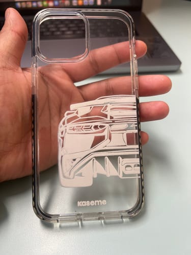 Customer's hand holding the Lambo Clear Case, showing its transparent material, white car graphic, and raised protective edges.