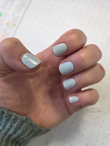 Eine Kundin zeigt ihre manikürten Hände mit den hellblauen UV-Gel-Nagelfolien in 'Sea Foam Blue'.