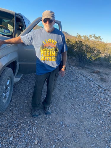 Customer wearing the blue 'I Love Peeing Outside' T-shirt while standing next to a vehicle in a desert.