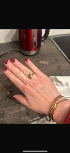 Customer's hand wearing a two-tone ring and several gold-colored bracelets.