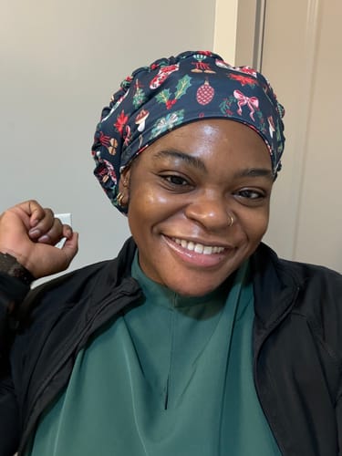 Customer smiling while wearing the slouchy DuoStyle Scrub Hat in the Holiday Cheer pattern.