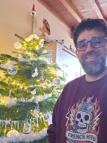Client portant le sweat bordeaux de la COLLECTION EREDITA devant un sapin de Noël.