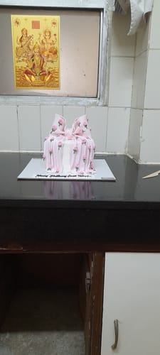 A reviewer's Floral Bow Girlfriend Cake, decorated with a large pink bow, sitting on a kitchen counter.