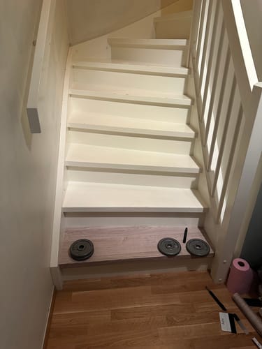 Kunde som legger Oak minimal kontaktplast på det nederste trinnet i en hvit trapp.