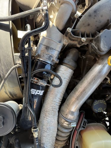 Customer's new black SPE 6.7L Powerstroke Cold Side Pipe with billet connector installed in a truck's engine bay.