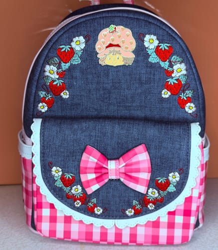 Customer's Strawberry Shortcake Loungefly mini backpack with a denim top, pink gingham bottom, and a large bow.