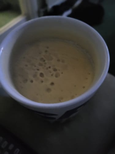 Close-up of a customer's mug filled with a frothy, prepared Rainbow Dust drink.