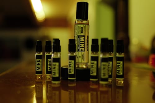 Cliente mostra il suo profumo SHAMROCK insieme a molti campioncini su un tavolo lucido.