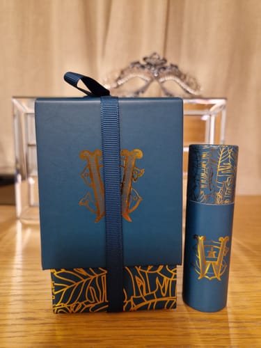 Customer shows the elegant blue and gold packaging for Tabac Soleil next to the complimentary travel-size item received.