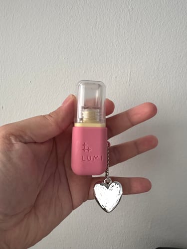 Customer holding the pink Deep Hydration Lip Oil bottle with a silver heart charm.