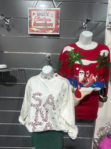 Customer's festive Christmas sweatshirts displayed on two mannequins in a store setting.