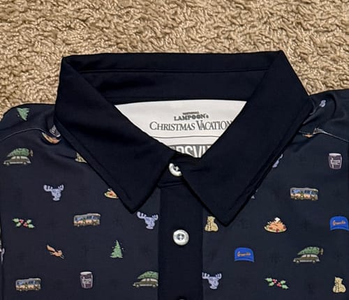 Close-up of a customer's 'Christmas Vacation' polo, showing the navy collar and a pattern of small movie icons.