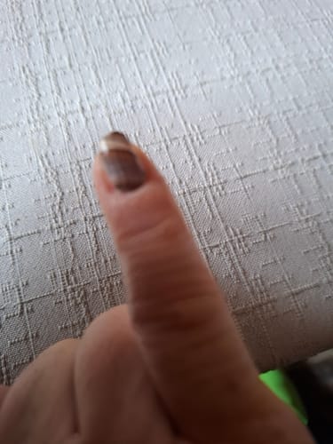 Unscharfe Nahaufnahme des Daumens eines Kunden, der die August Ombré Nagelfolie trägt.