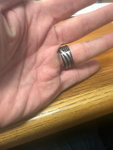A customer's hand wearing the Don't Tread On Me Ring, showing the black and silver American flag design.
