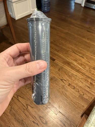 Customer holding a new replacement Jura water filter still in its clear plastic packaging.