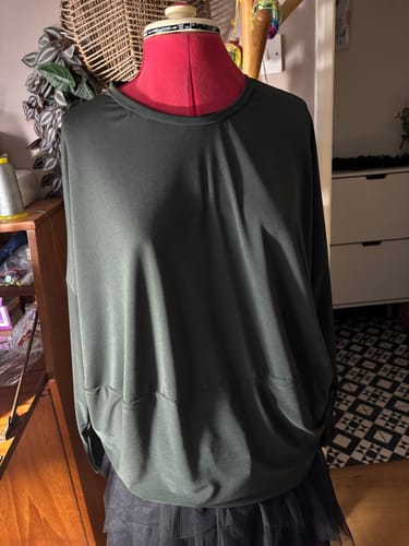 Customer's dark green dolman-sleeve top made from the elastane fabric, displayed from the front on a dress form.
