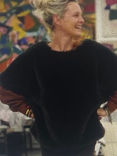 Cliente souriante portant le Poncho Douillet Pétronille, qui semble ample et doux.