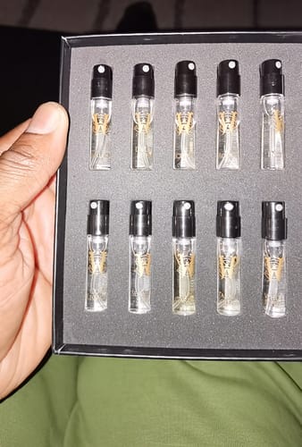 Reviewer holding the Men's Discovery Set open, showing ten small fragrance sample vials arranged in a box.