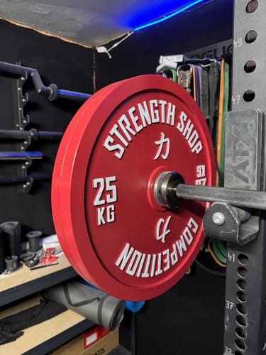 Reviewer's red 25kg Strength Shop Calibrated Plate loaded on a barbell in a power rack.