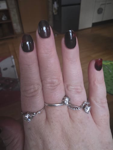 Nahaufnahme der Hand einer Kundin, die die tiefroten, glänzenden Starry Garnet UV-Gelnägel trägt.