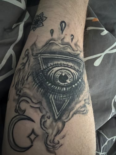 A reviewer's detailed black and grey tattoo of an eye on their arm, looking vibrant after using Alpha Tattoo Butter.