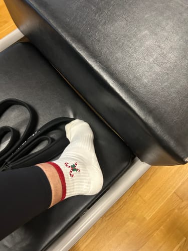 A reviewer wearing the white Candy Christmas socks with red stripes and an embroidered candy cane design.
